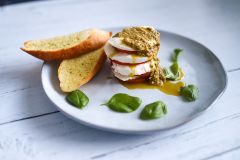 Mozzarella cheese, basil, tomatoes, and garlic breads on a plate.